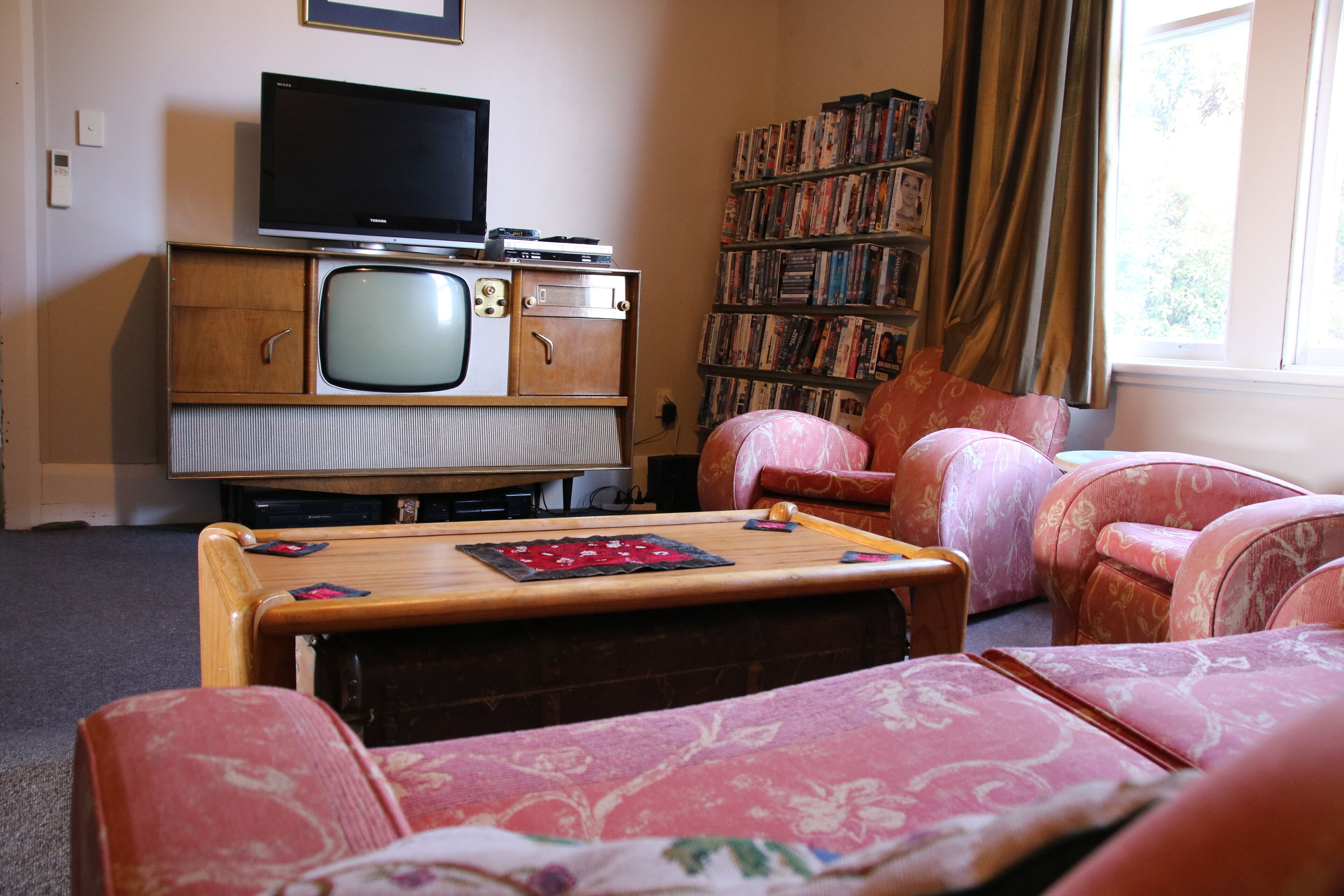 A living room with a vintage television set, a bookshelf, and patterned furniture.