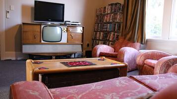 A living room with a vintage television set, a bookshelf, and patterned furniture.