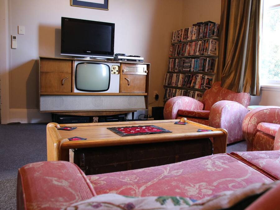 A living room with a vintage television set, a bookshelf, and patterned furniture.