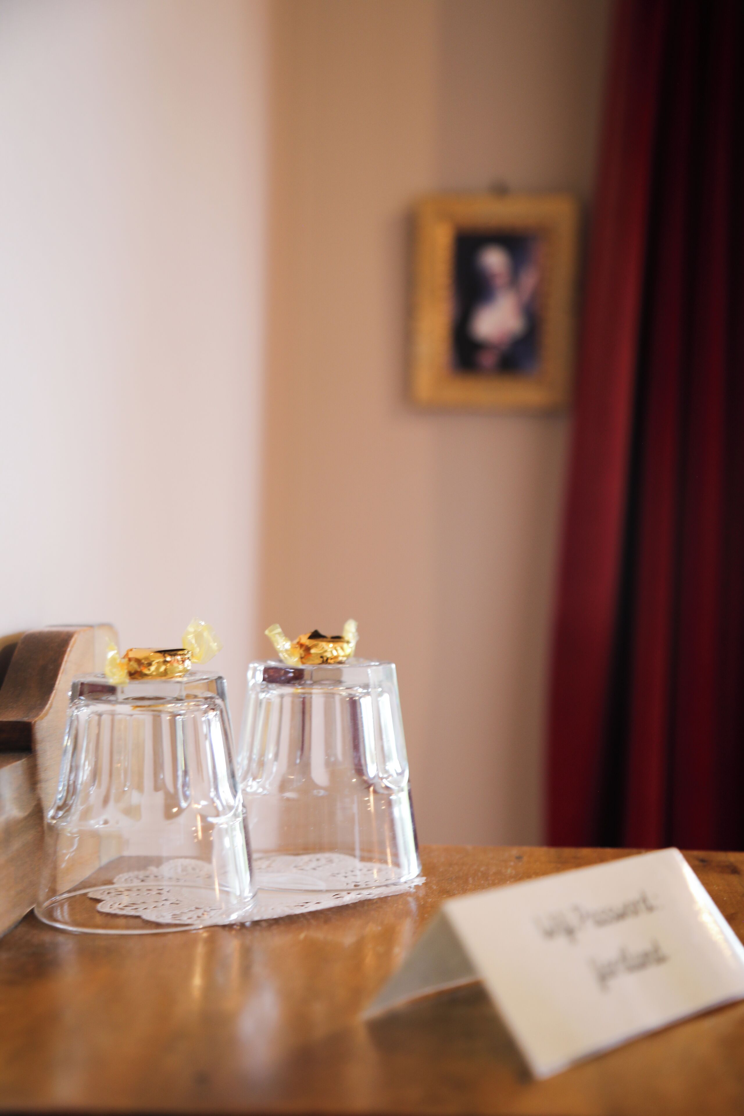 Two clear glass bottles with gold caps on a wooden table, a doily, and a name card reading "Mr. & Mrs. Smith's".