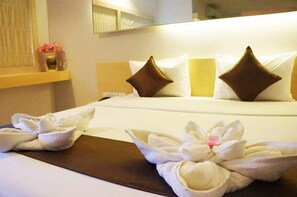A hotel room with a neatly made bed, pillows, and a decorative flower arrangement on the bed. - Khuangsingh Residence (Chiang Mai)