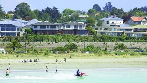 Une zone résidentielle côtière avec des maisons, une plage de sable et des personnes pratiquant des activités nautiques.