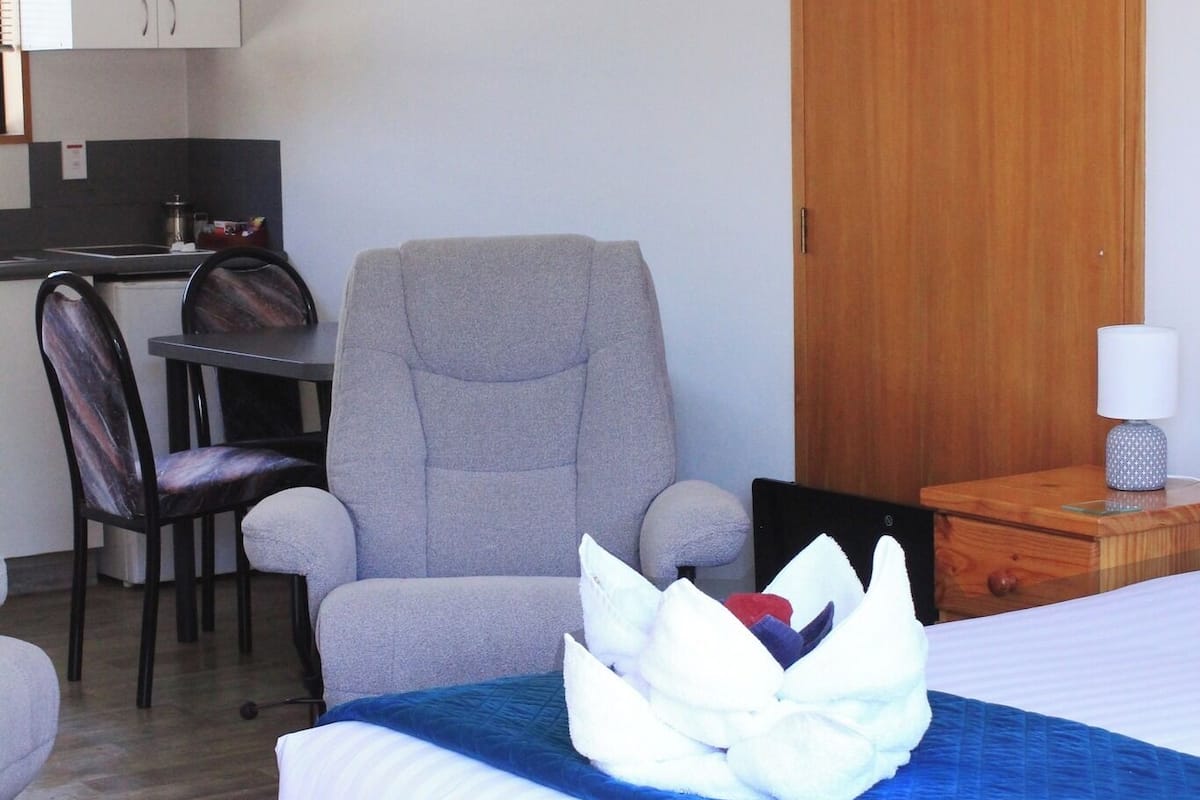 Ein Hotelzimmer mit Bett, Stuhl, Schreibtisch und Kleiderschrank.
