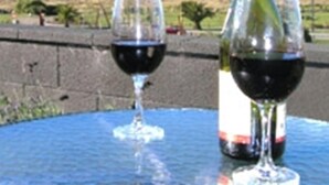 Une table avec une bouteille de vin rouge et deux verres à vin.