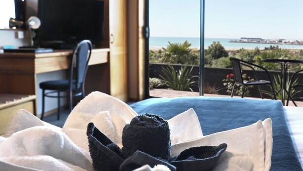 Une chambre d’hôtel équipée d’un lit, d’un bureau, d’une chaise, d’une télévision et offrant une vue sur la plage.