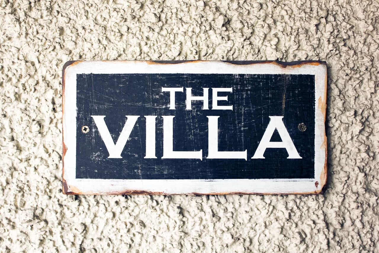 Een bord met de tekst 'THE VILLA' op een gespiegelde achtergrond.