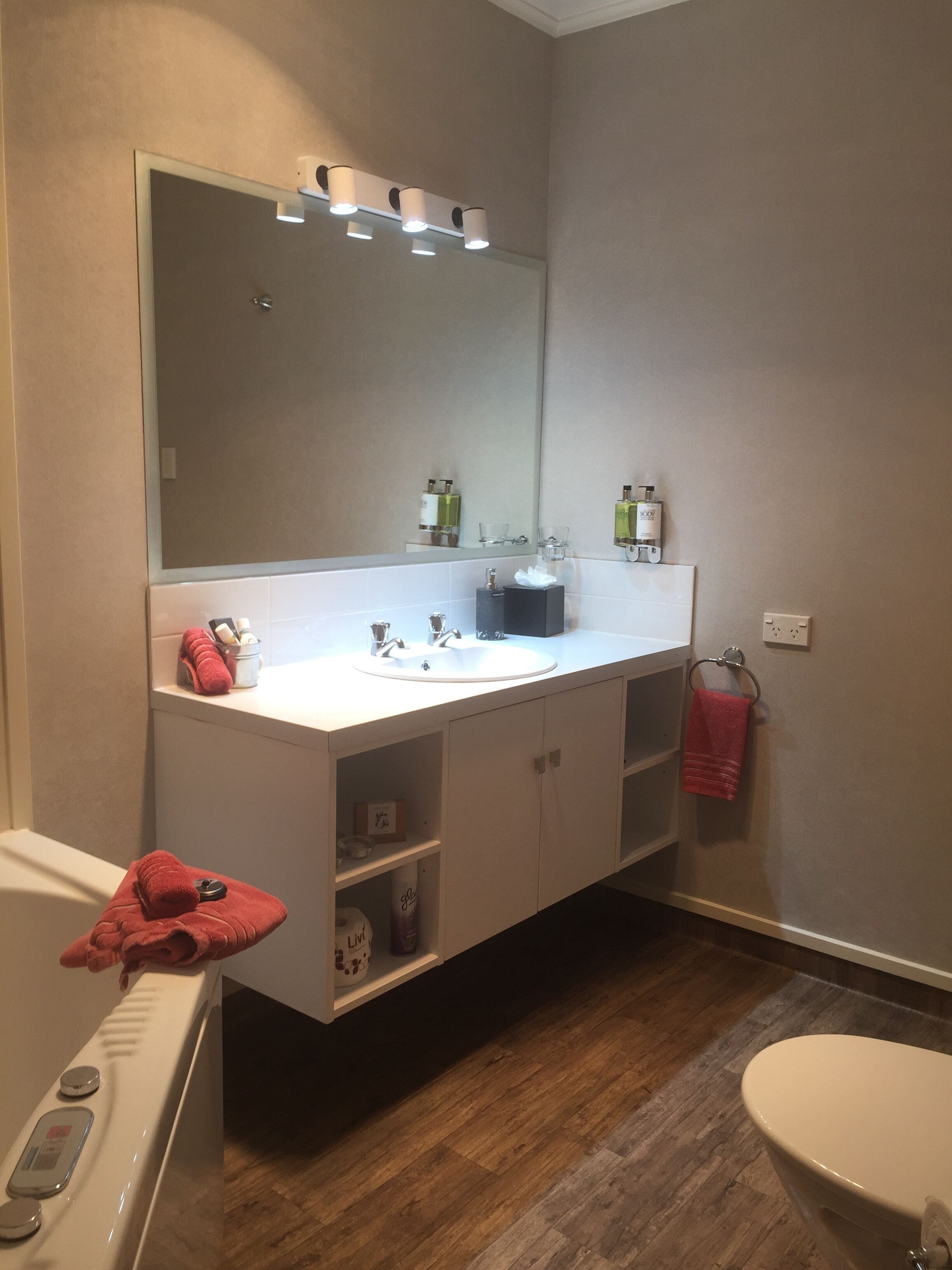 A bathroom with a white sink, mirror, and a red towel on the floor.