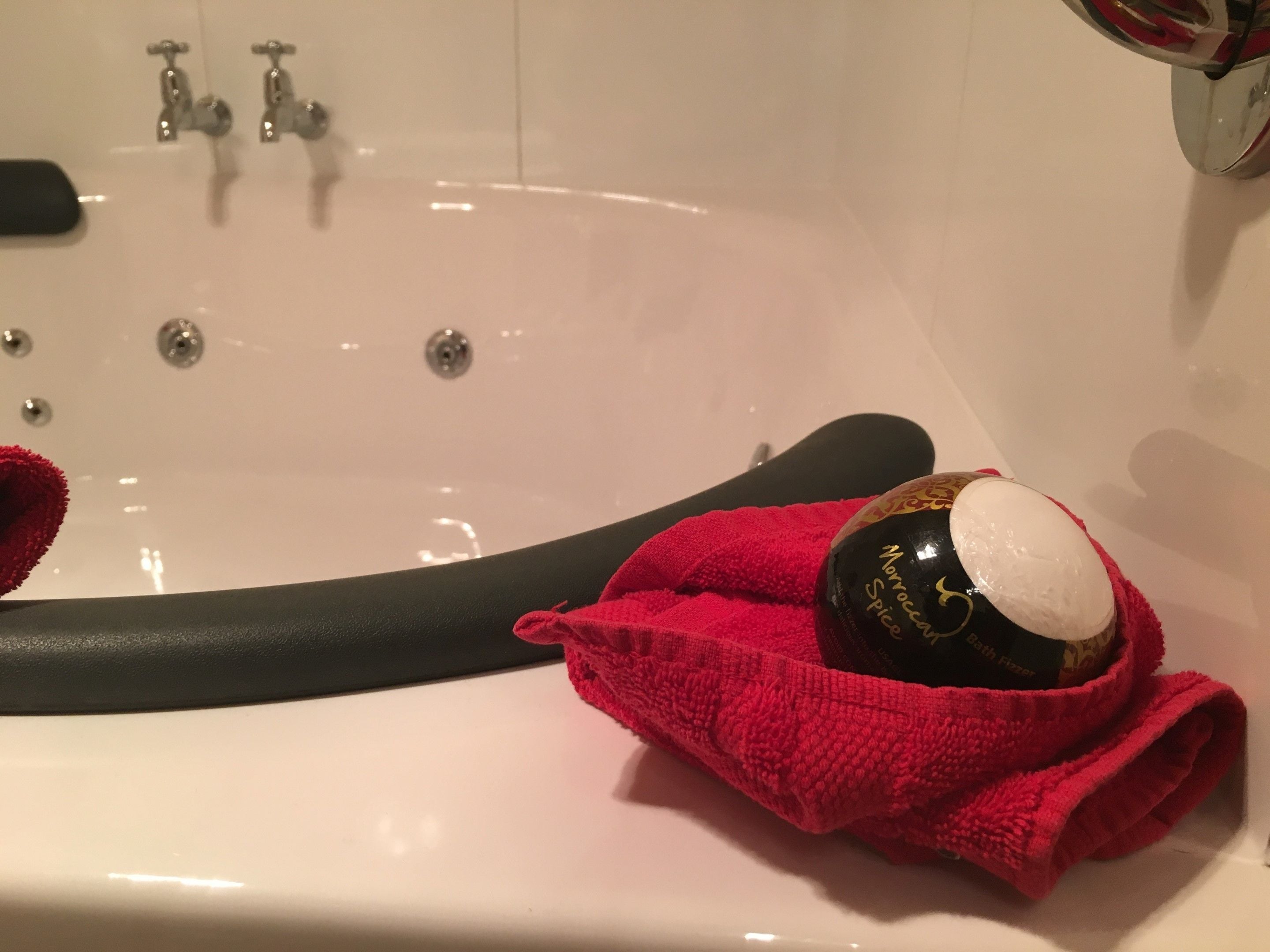 A bathtub with a black hose, a red towel, and a bottle of Monocera Both Fizzers.