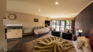 Una habitación de hotel con una cama, un escritorio pequeño, una silla, un ventanal y una kitchenette.