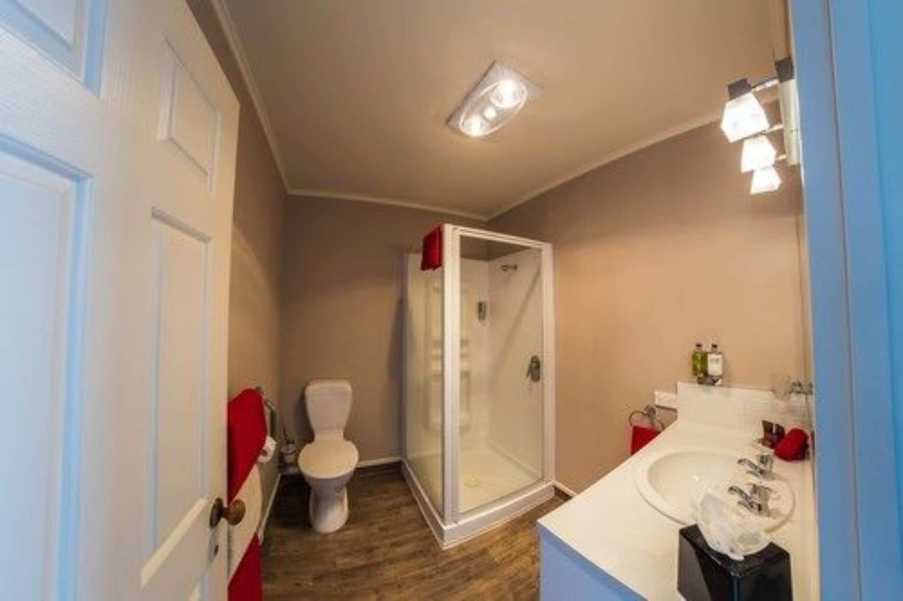 A compact bathroom with a toilet, a glass-enclosed shower, and a sink with a mirror.