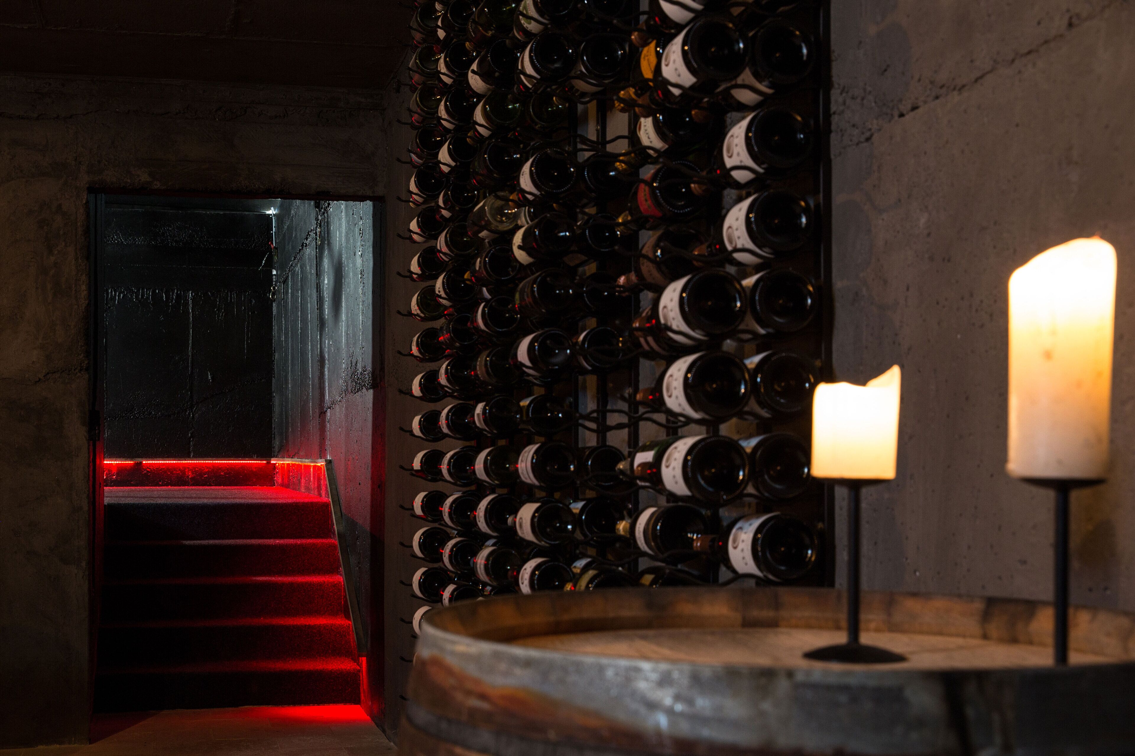 Ein Weinkeller mit einer rot beleuchteten Treppe und einer Weinregalwand.