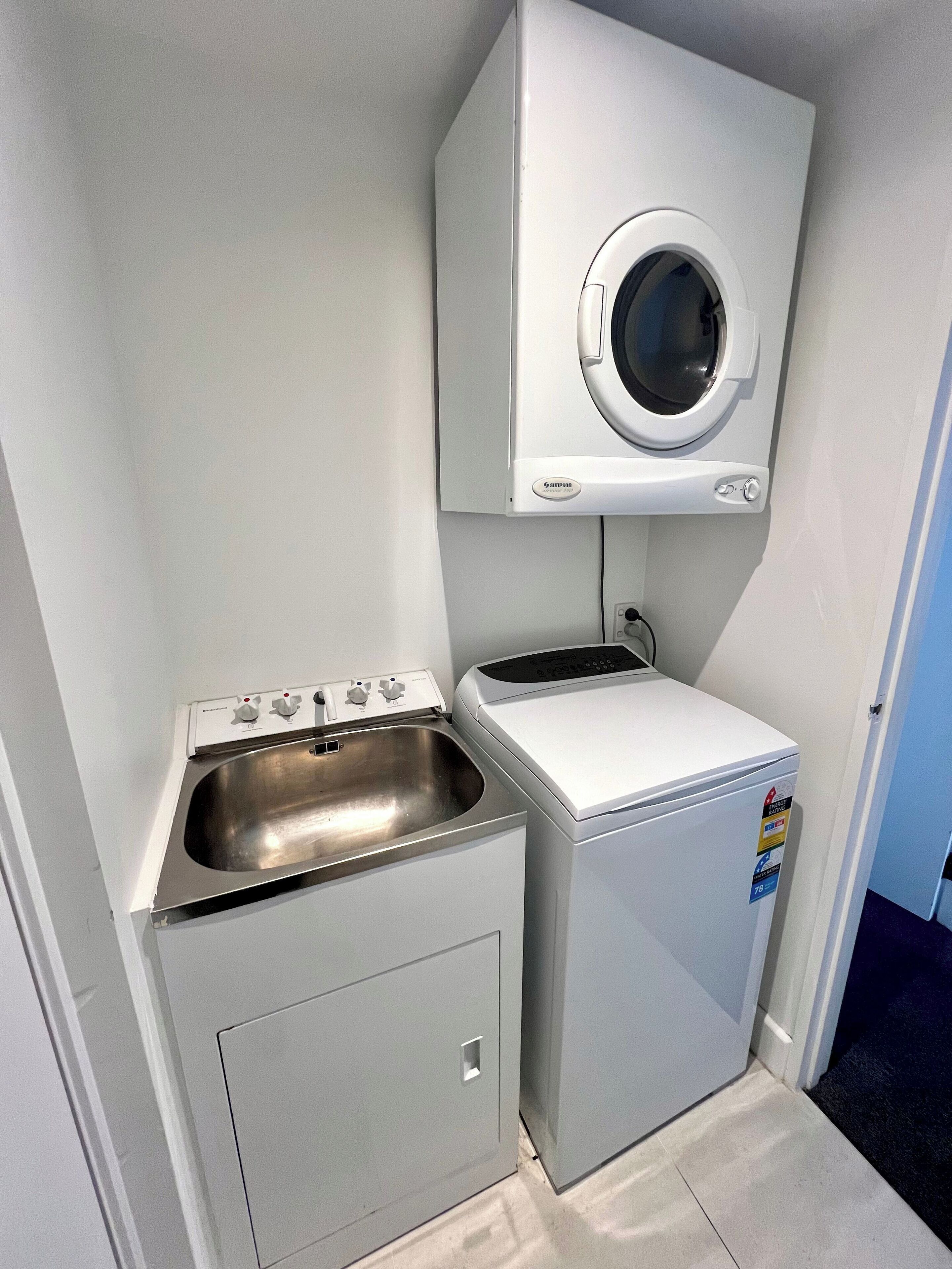 A compact laundry area with a washing machine, a dryer, and a sink.