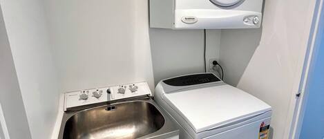 A compact laundry area with a washing machine, a dryer, and a sink.