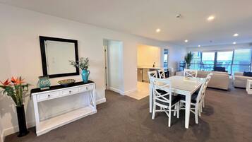 A modern living room with a dining area, white furniture, and a view of the balcony.