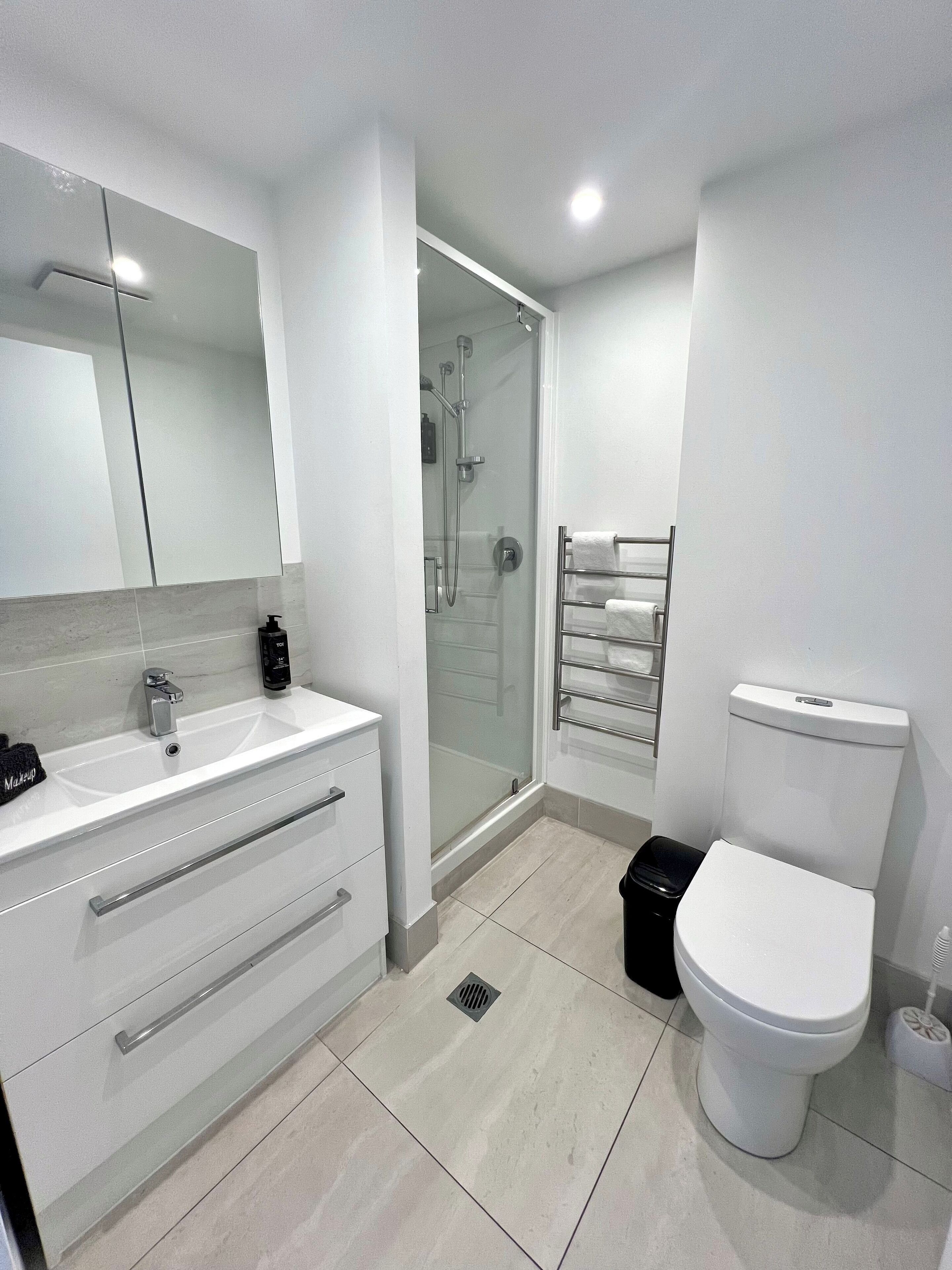 A modern bathroom with a white sink, mirror, and toilet.
