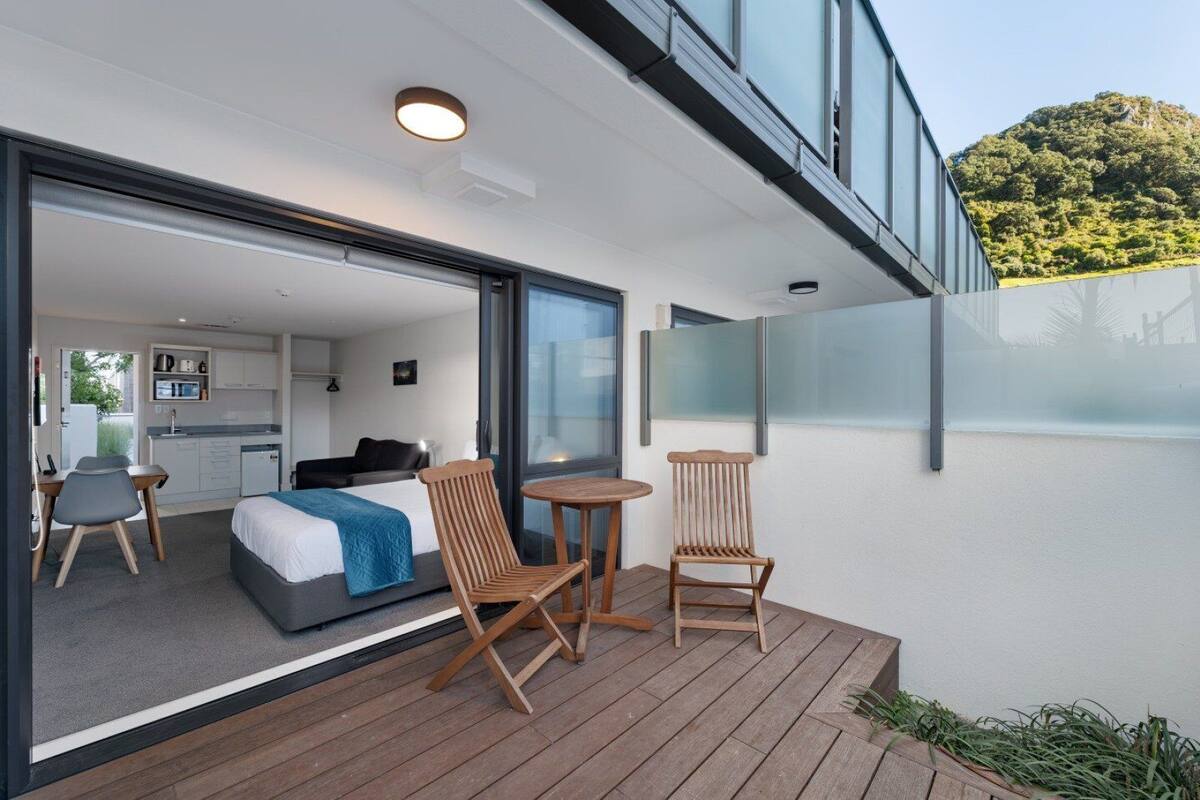 A modern hotel room with a balcony, a bed, a desk, and a chair.