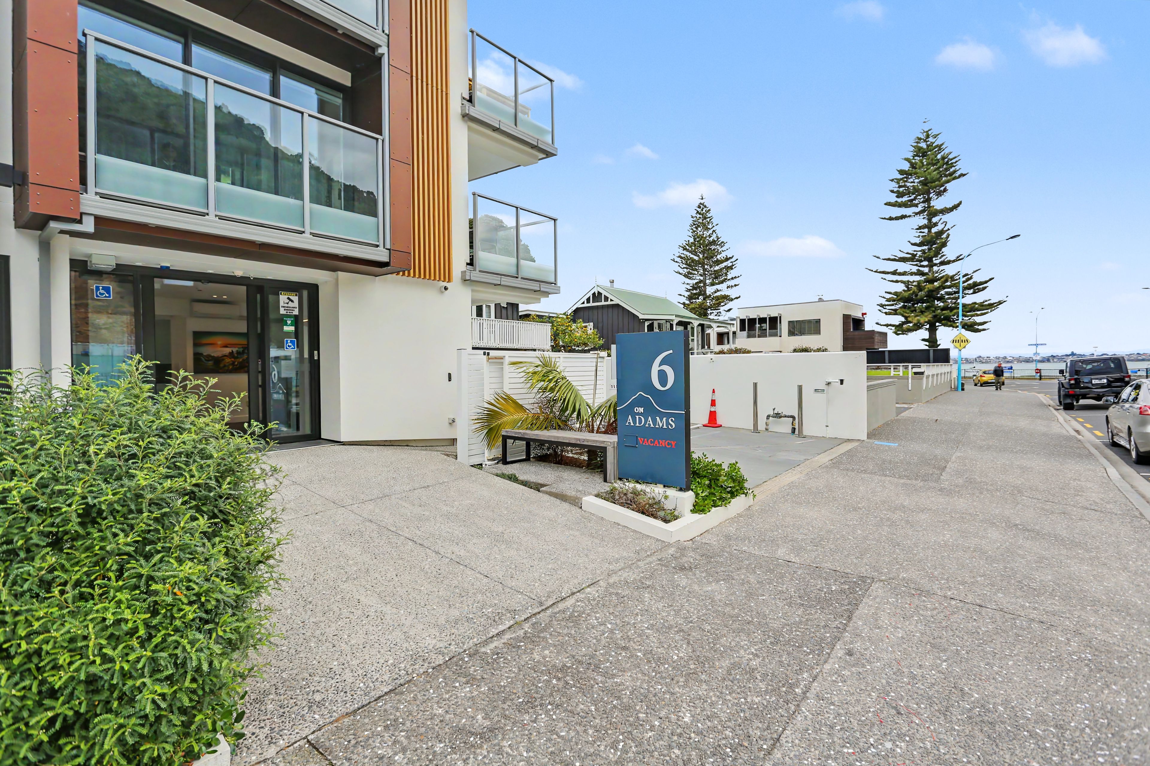 A modern building with a wheelchair-accessible entrance, a sign indicating a vacancy, and a number 6 sign.