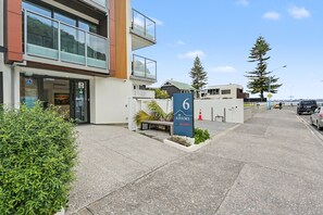 A modern building with a wheelchair-accessible entrance, a sign indicating a vacancy, and a number 6 sign. - 6 on Adams  (Tauranga)