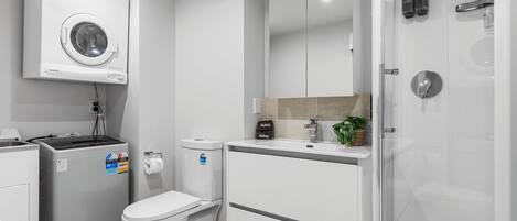 A modern bathroom with a built-in washing machine, toilet, and shower.