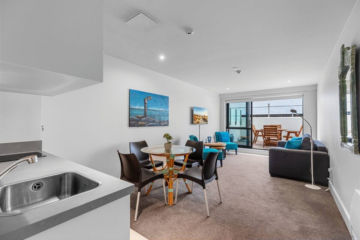 A modern living area with a kitchen, dining table, and seating.