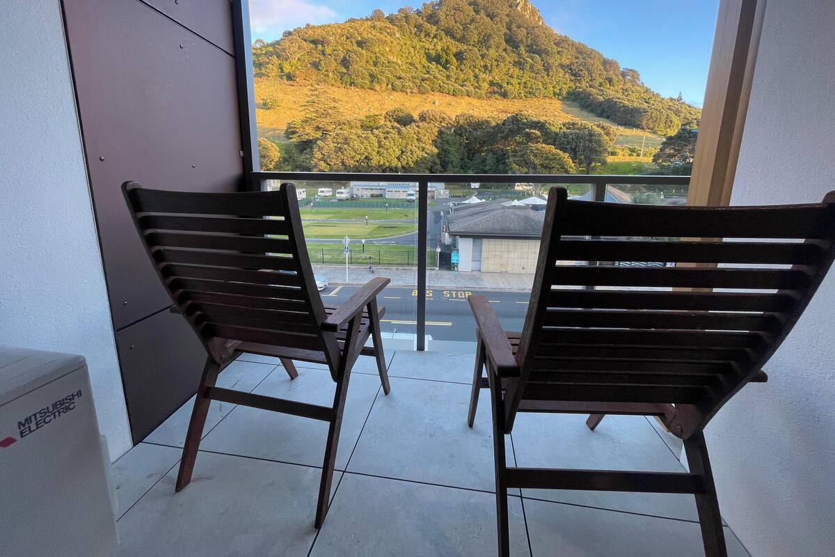 A balcony with two wooden chairs and a Mitsubishi Electric refrigerator.