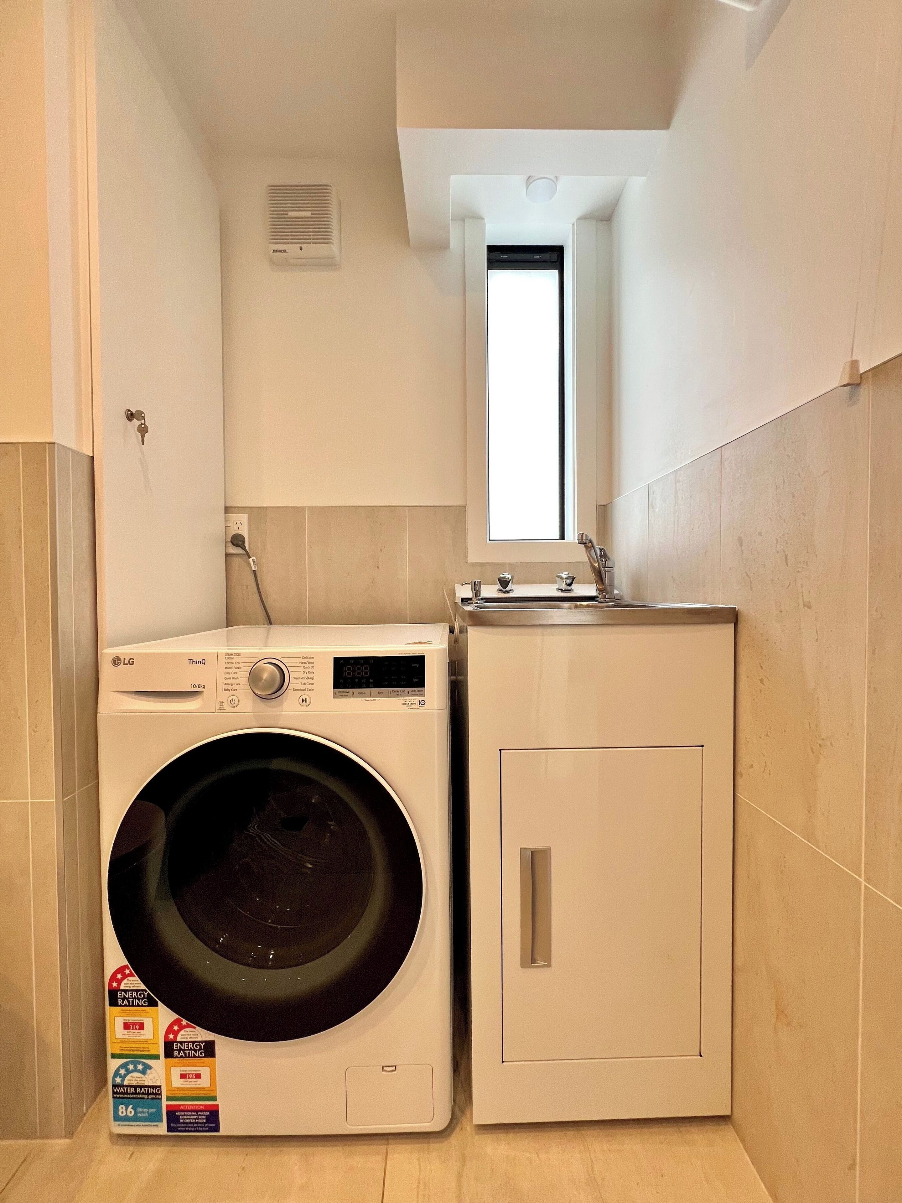 Een kleine wasruimte met een LG wasmachine en een wit kastje.
