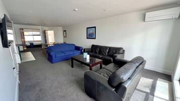 A living room with a blue sofa, a black leather sofa, a coffee table, and a TV.