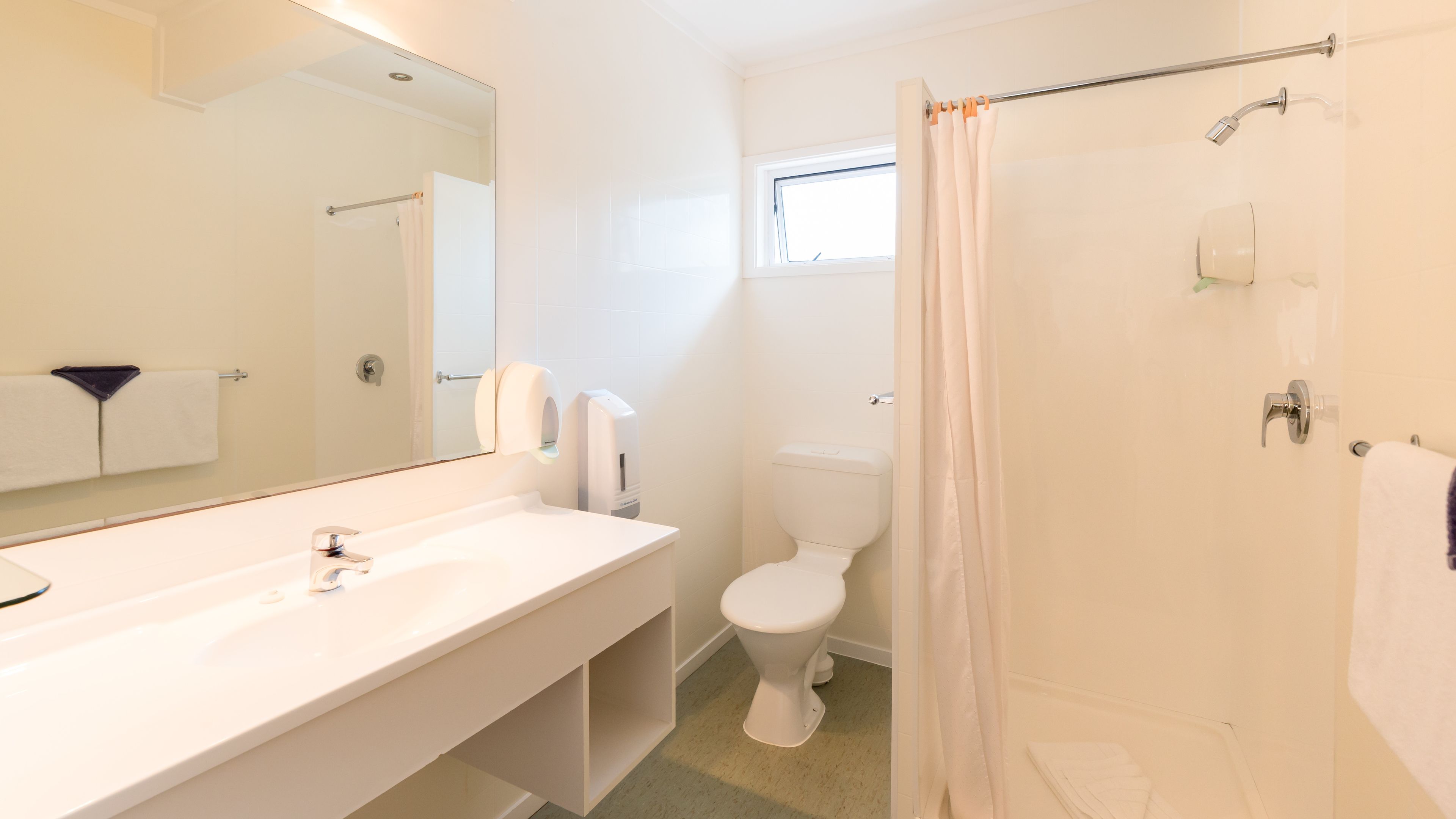 A bathroom with a white sink, toilet, and shower curtain.