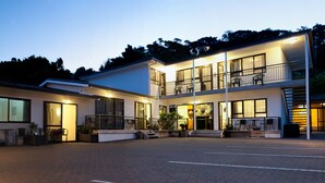 Een modern hotel met een ruim buitengebied, meerdere balkons en een goed verlichte entree.