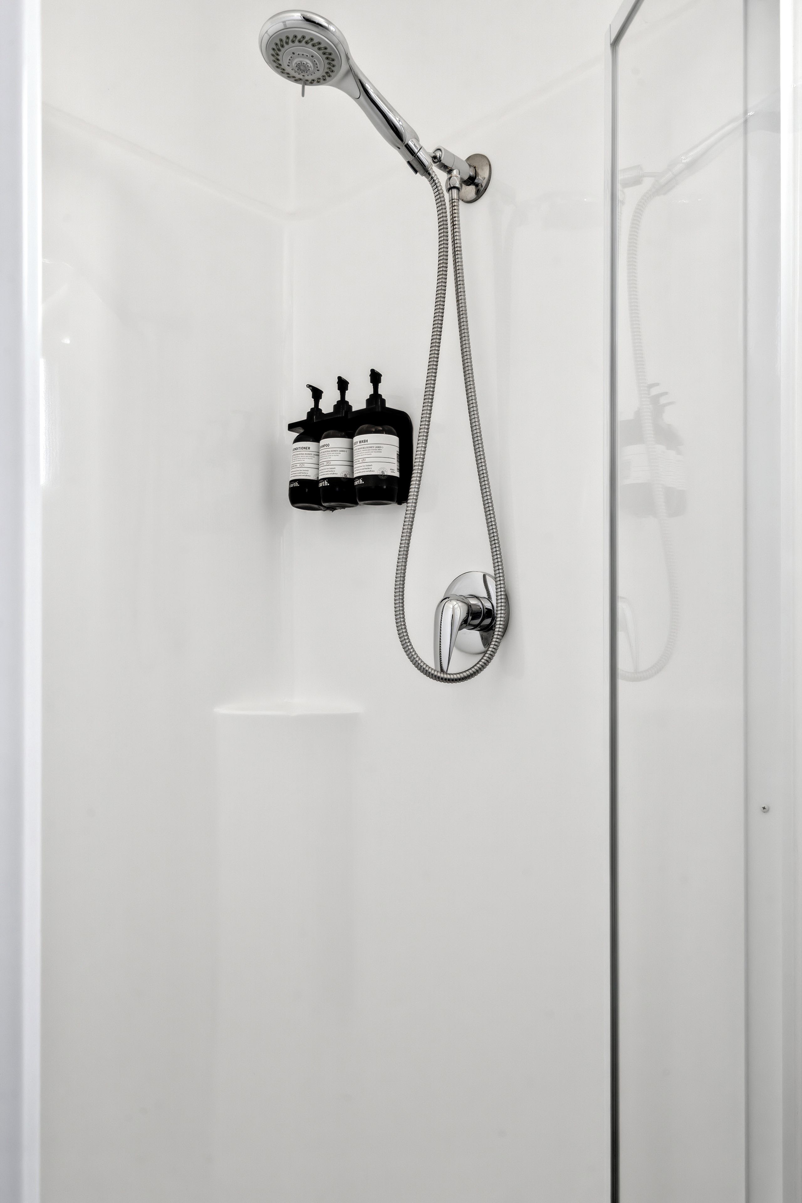 A shower with a handheld showerhead and a handheld shower attachment.