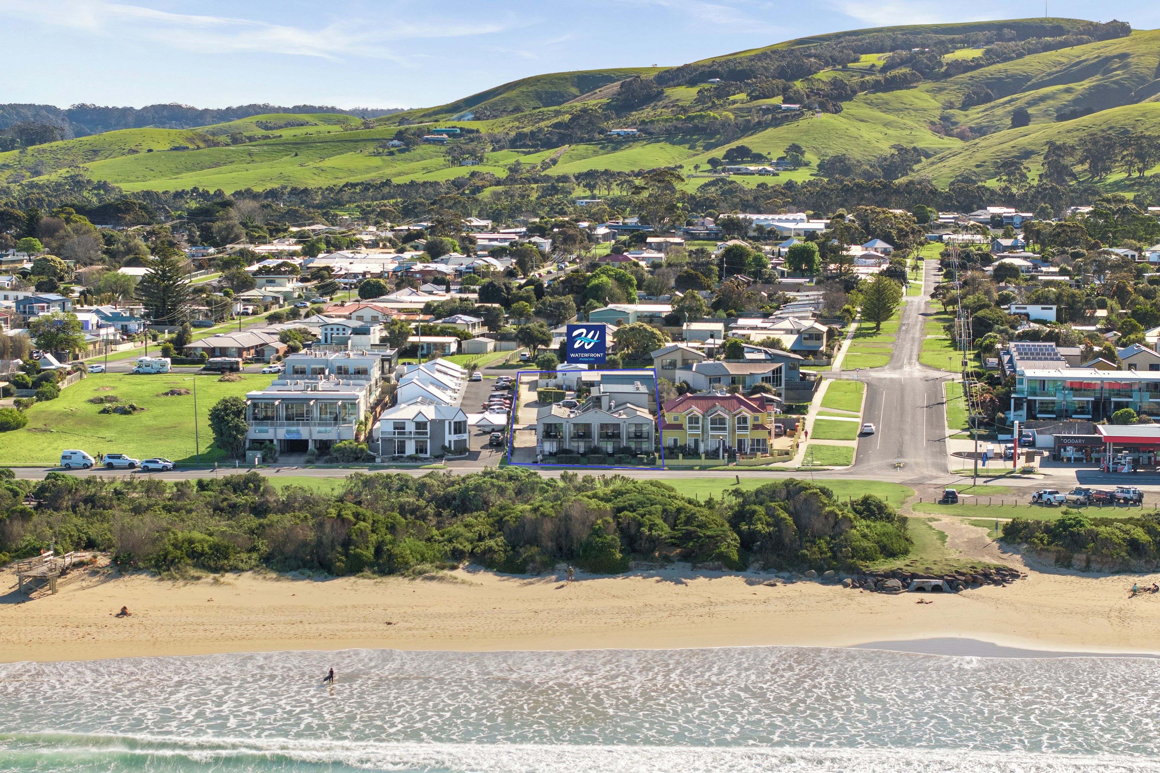 Uma cidade costeira com um edifício de destaque à beira-mar, um grande letreiro, uma estrada principal e uma praia ao primeiro plano.