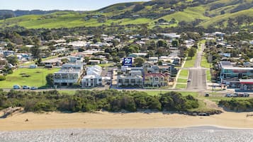 Uma cidade costeira com um edifício de destaque à beira-mar, um grande letreiro, uma estrada principal e uma praia ao primeiro plano.