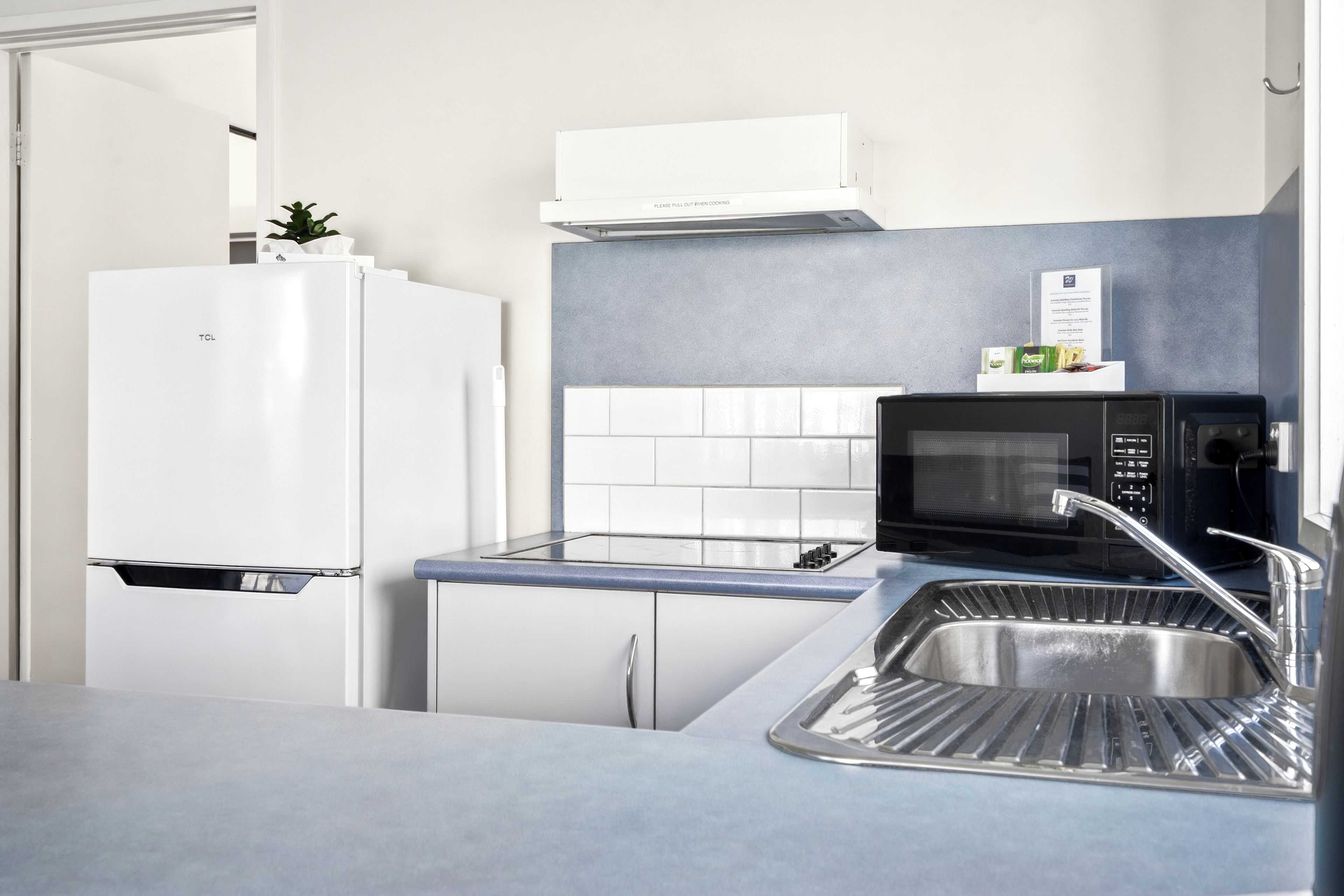 Una cuina moderna amb nevera blanca, microones i un rentaplat.
