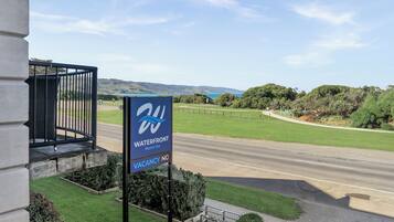 A sign for a Waterfront Motor Inn with a view of a road and greenery.