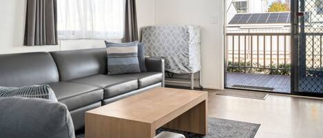 Ein modernes Wohnzimmer mit einem grauen Sofa, einem Holztisch und einem gemusterten Sessel.