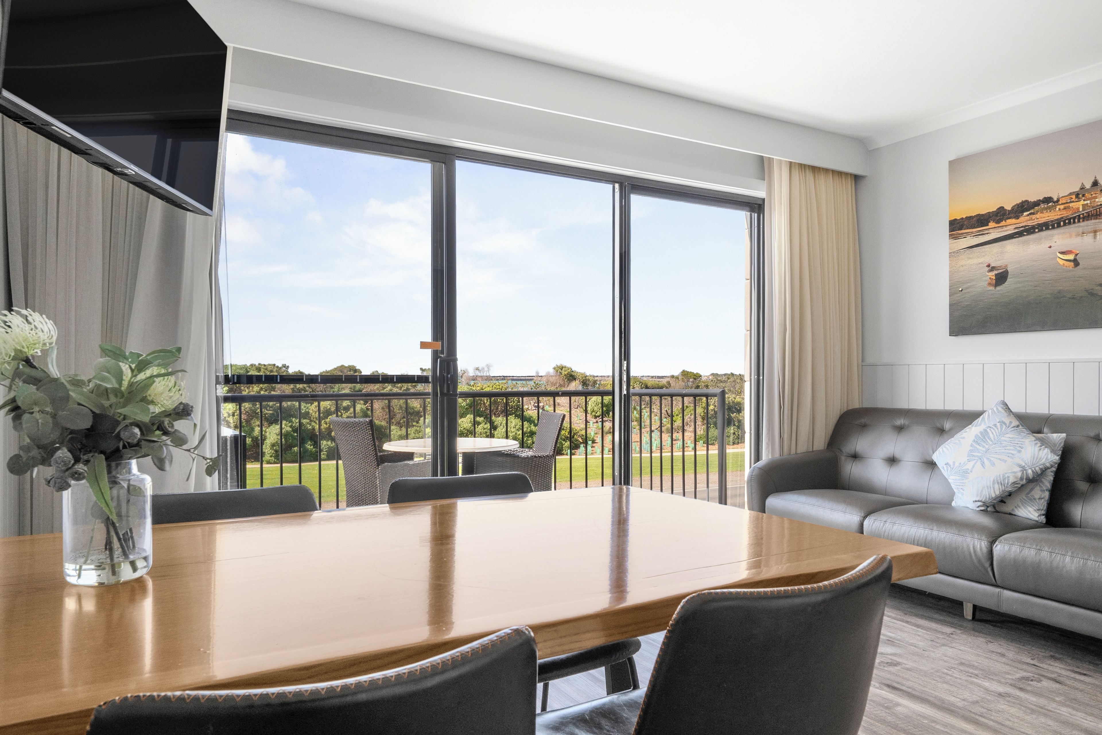 A modern living room with a dining area, large windows, and a view of the outdoors.