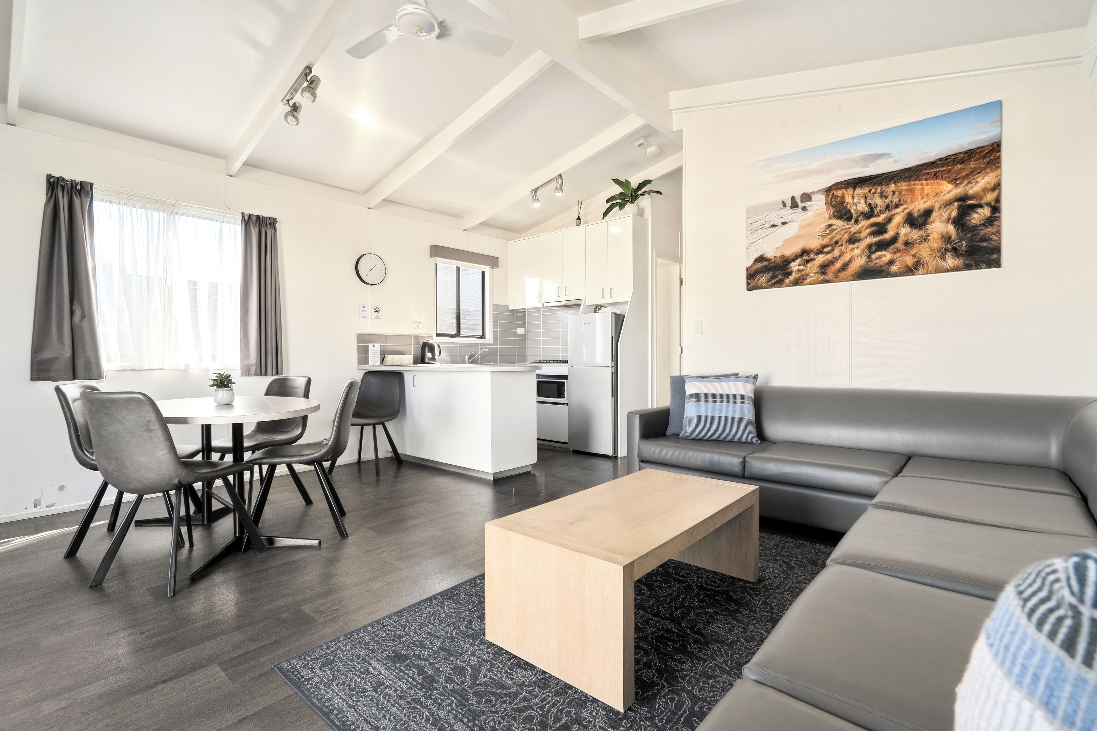 En moderne stue med sofa, sofabord og spiseområde med stole.