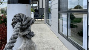 A white bollard with a rope tied around it, a building with large windows, and a gravel pathway. - Apollo Bay Waterfront Motor Inn (Apollo Bay)