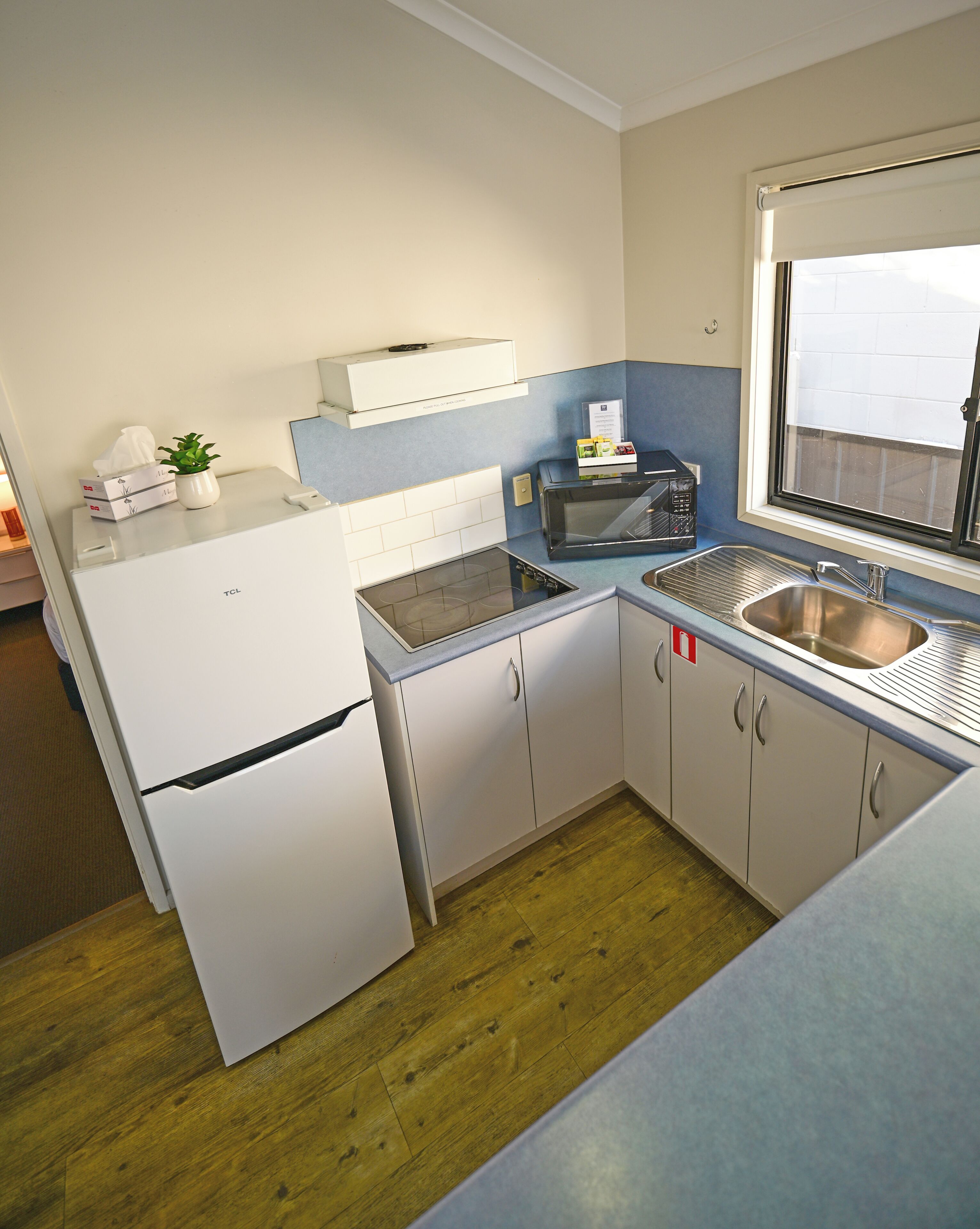 Cocina compacta con refrigerador, microondas, tostadora y pileta.