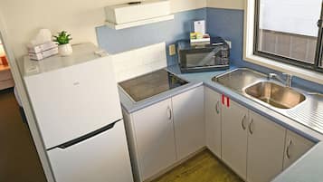 Cocina compacta con refrigerador, microondas, tostadora y pileta.
