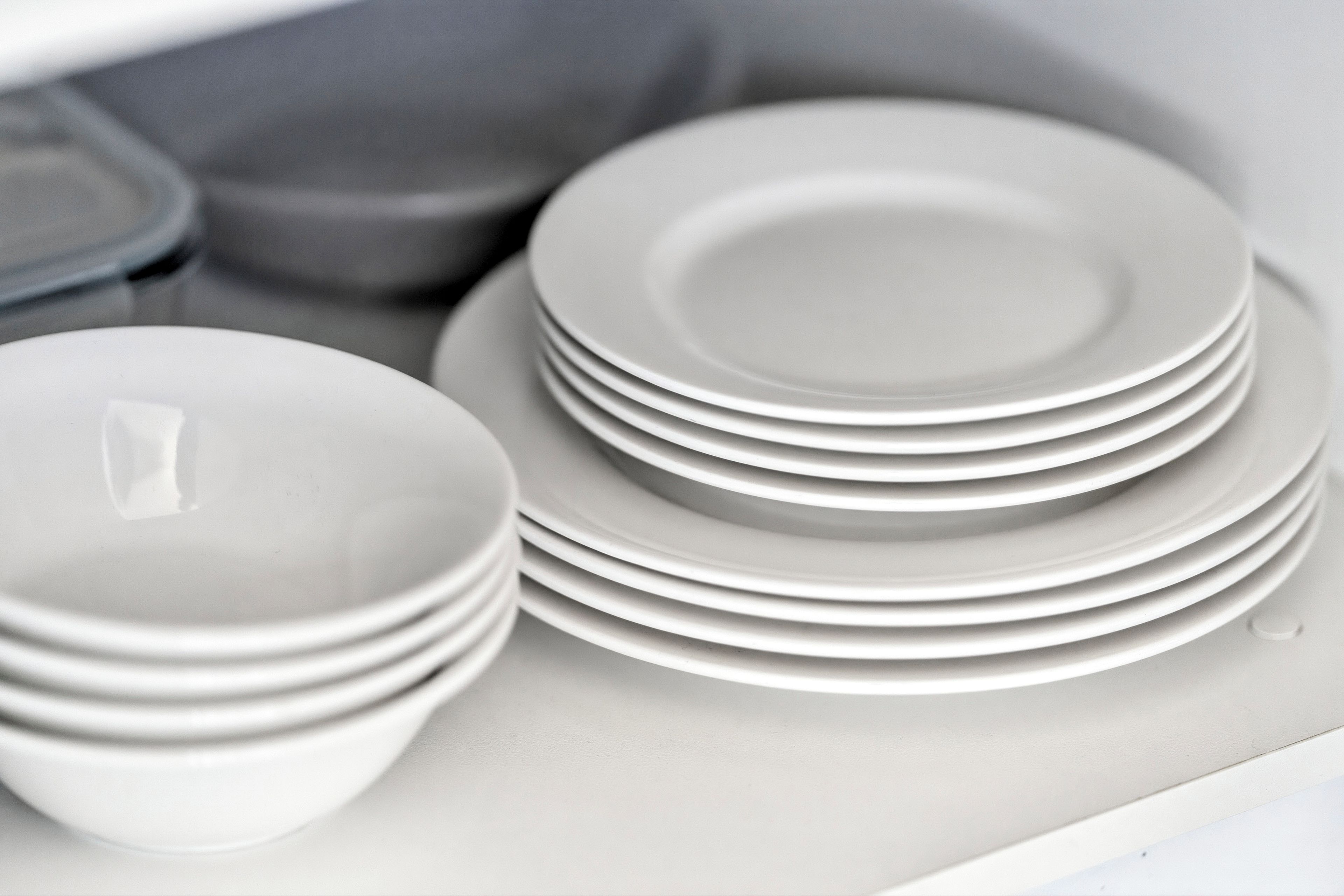 Una pila de platos y tazones blancos en un armario de cocina.