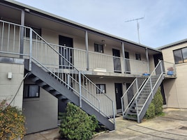 Un edificio de varios pisos con escaleras exteriores, balcones y una antena visible.