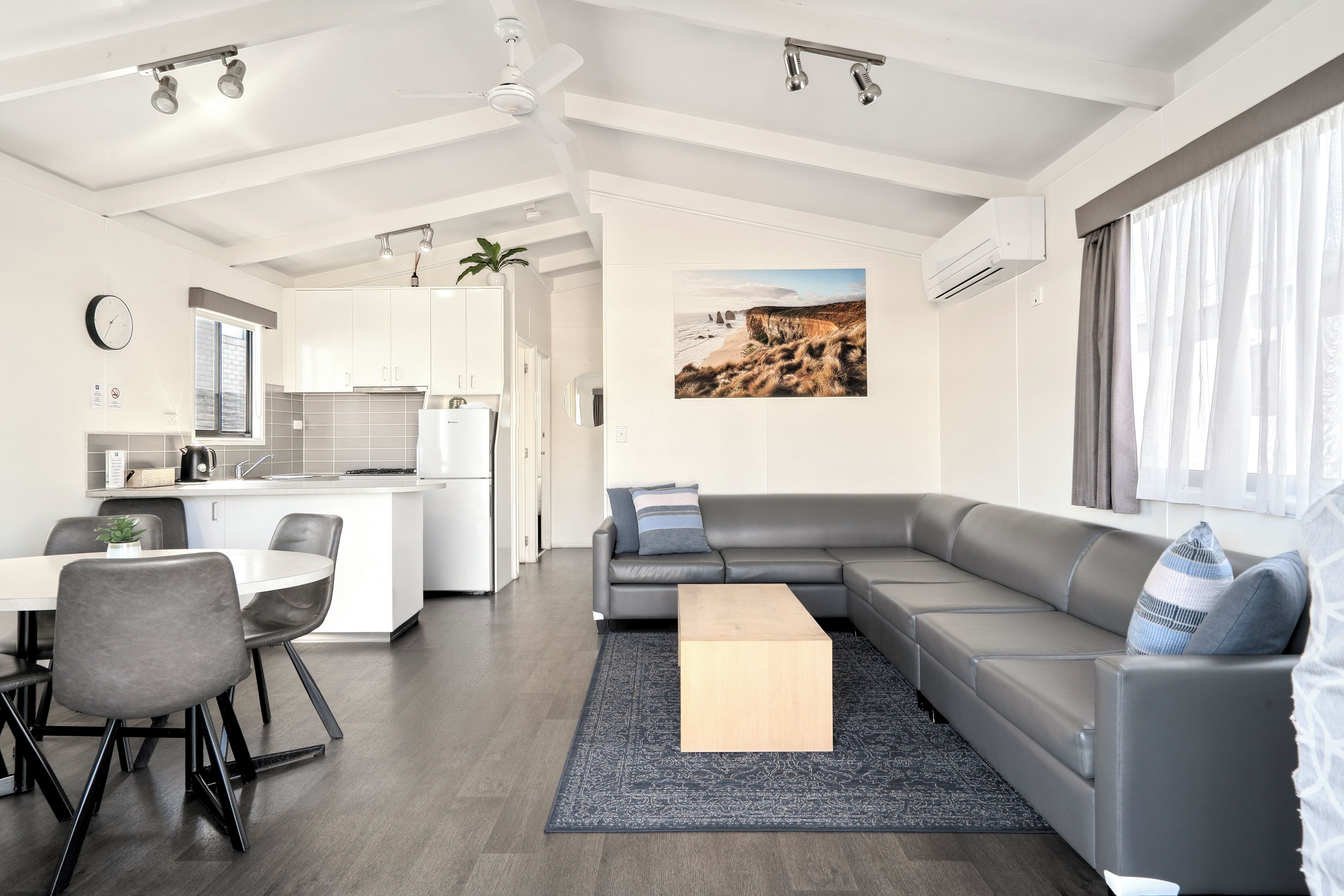 Un espacio habitable moderno con cocina, comedor y un sofá grande de color gris.