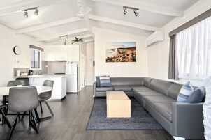Un espacio habitable moderno con cocina, comedor y un sofá grande de color gris.