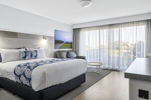Habitación de hotel moderna con una cama grande, una pequeña zona de estar y vistas al exterior.