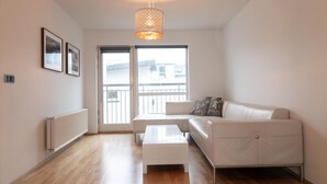 A modern living room with a white sofa, a white coffee table, and a hanging light fixture.