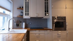 A modern kitchen with white cabinets, a stainless steel oven, and a wooden countertop.