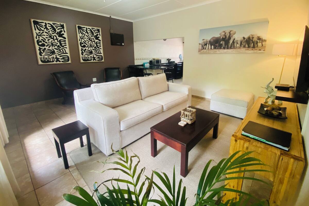 A living room with a sofa, a coffee table, a TV, and a painting on the wall.