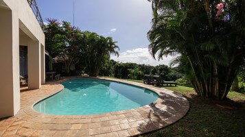 Una piscina al aire libre, sombrillas, sillones reclinables de piscina