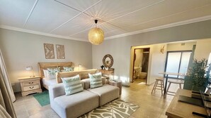 A bedroom with a bed, bedside tables, a hanging light fixture, a bathroom visible through an open door, and a dining area with a table and chairs. - Little Eden St Lucia (St. Lucia)